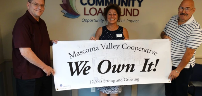 Photo of Darrel Brock, Mascoma Valley Treasurer; Michelle Supry of ROC-NH; and Lenny Beliveau, Mascoma Valley President, holding a We Own It! banner at the Community Loan Fund in Concord.