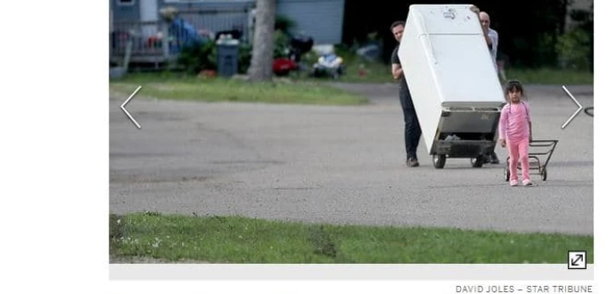 Screen shot of article with accompanying photo showing people forced to leave their community moving a refrigerator down the street.