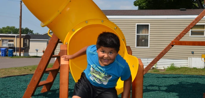 Photo showing boy emerging from mouth of curvy slide at Park Plaza Co-op in Fridley, Minn.