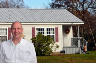 Photo of Paul Bradley in front of a manufactured home in a New Hampshire co-op.