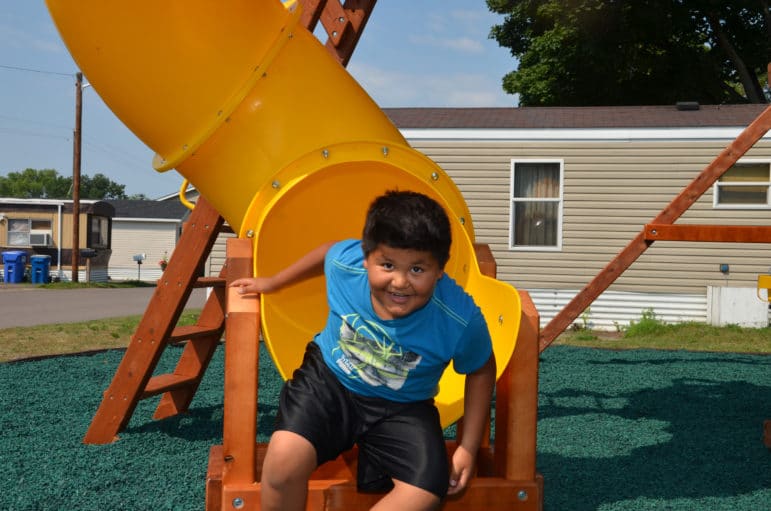 Photo showing boy emerging from mouth of curvy slide at Park Plaza Co-op in Fridley, Minn.