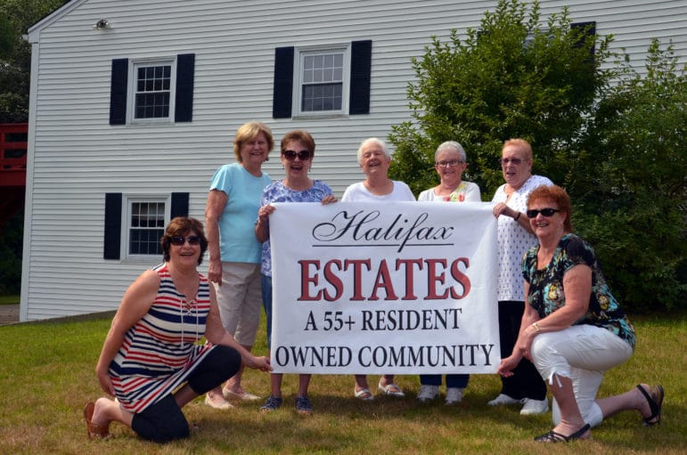 photo of Board Members holding banner displaying community name