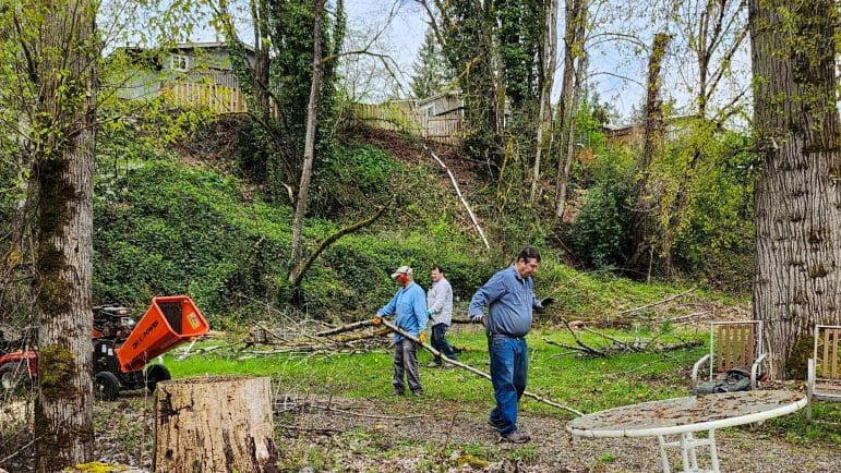 Photo shows workers clearing debris in a wooded setting at CRCC.