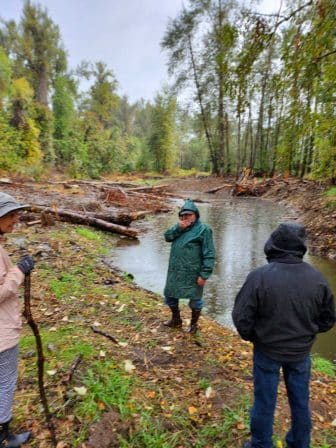 photo shows workers taking a break along the Clackamas River during a cleanup event.